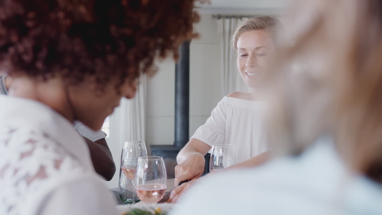Group Of Young Friends Sitting Around Table At Home Enjoying Meal Together