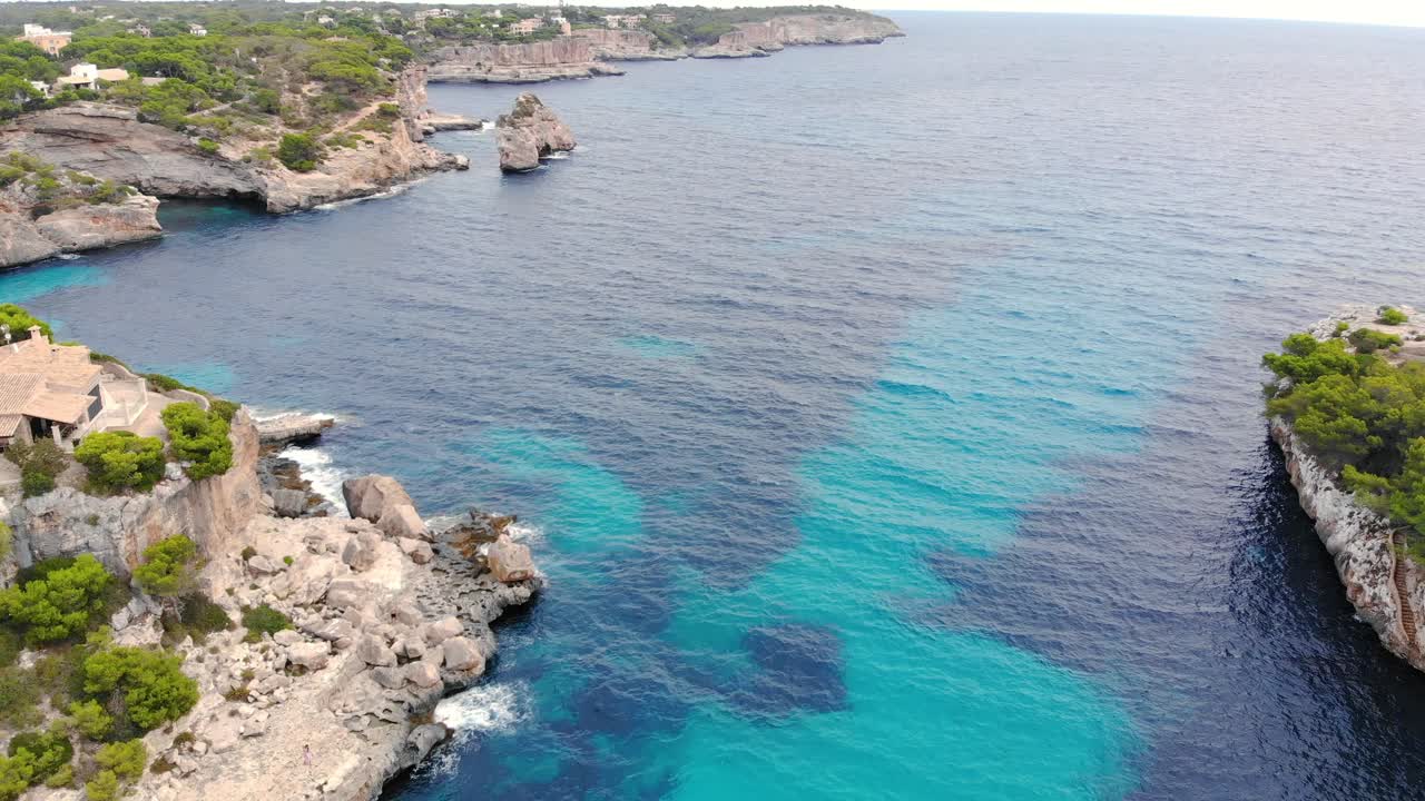 Luftfoto over Mallorcas krystalklare blå vand, omgivet af klippekyster i Spanien.
