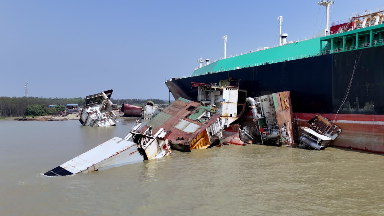 Cinematic revealing drone shot of a wreckage near a cargo ship in a ship graveyard in Bangladesh