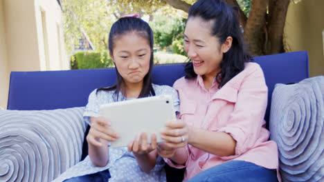 mother and daughter relaxing on couch and using digital tablet 4k