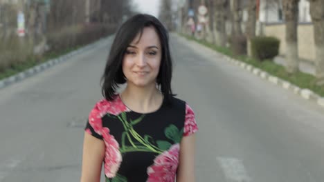 Attractive-young-woman-in-a-dress-with-flowers-turns-to-camera-and-smiles