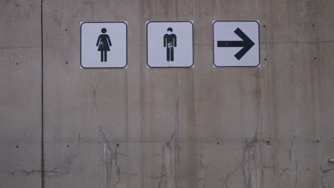 young woman teenager walking towards and away from male and female restroom sign outdoors in the cold