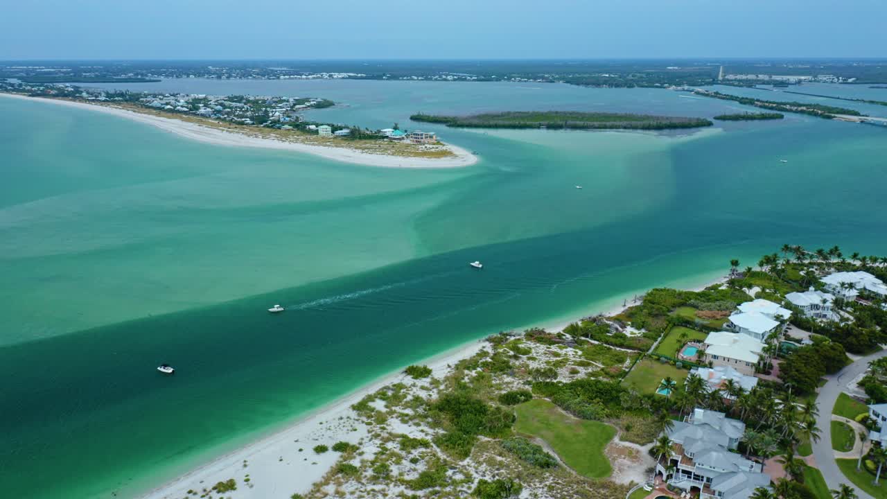 Boats cruise along the deep turquoise channel of Stump Pass beside Manasota Key on Florida’s Gulf Coast, bordered by sandbars, shallow water gradients, and waterfront homes overlooking Lemon Bay