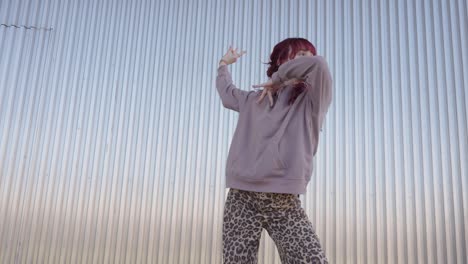young urban dancer performing in front of metal wall