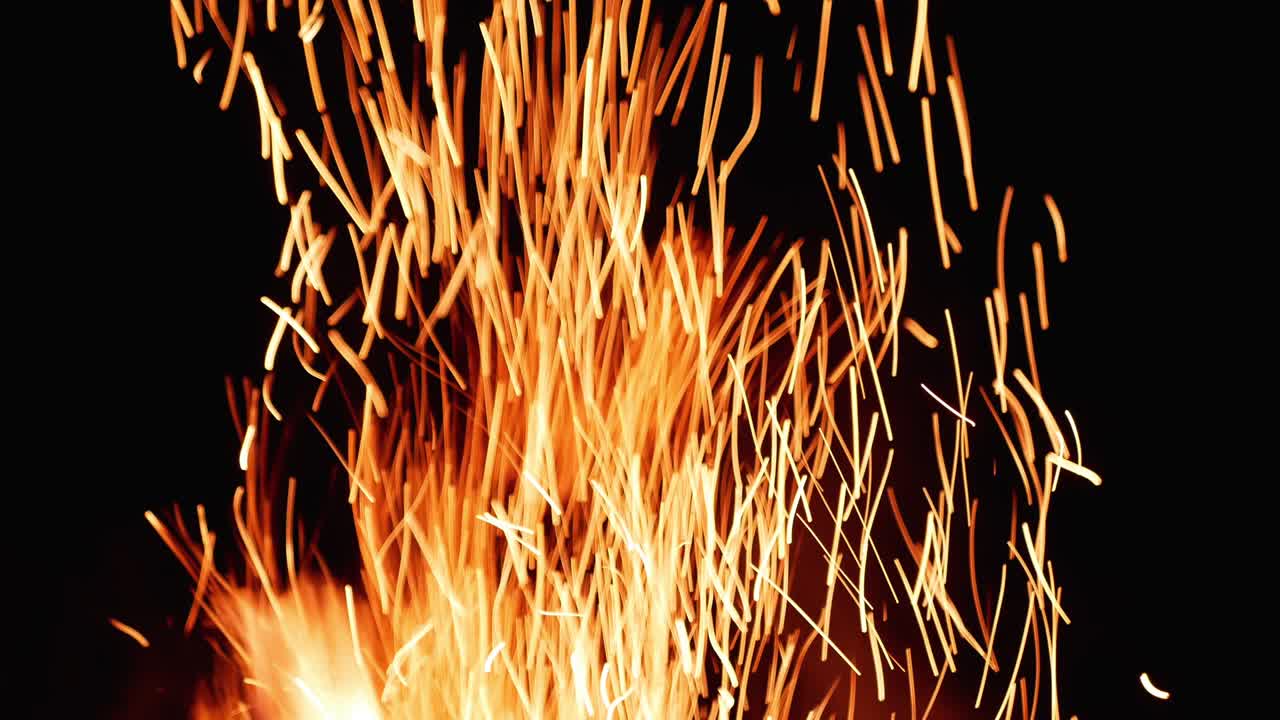 горящие красные горячие искры поднимаются с большого огня в ночном небе.