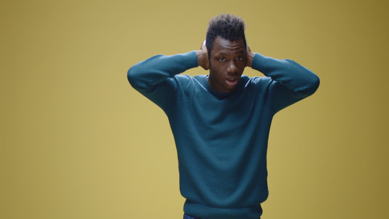 Young African American man covering his ears to block out noise