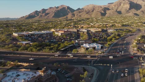 imágenes aéreas de drones de la concurrida plaza de tucson, arizona, durante el día con montañas en el fondo, coches conduciendo por la carretera.