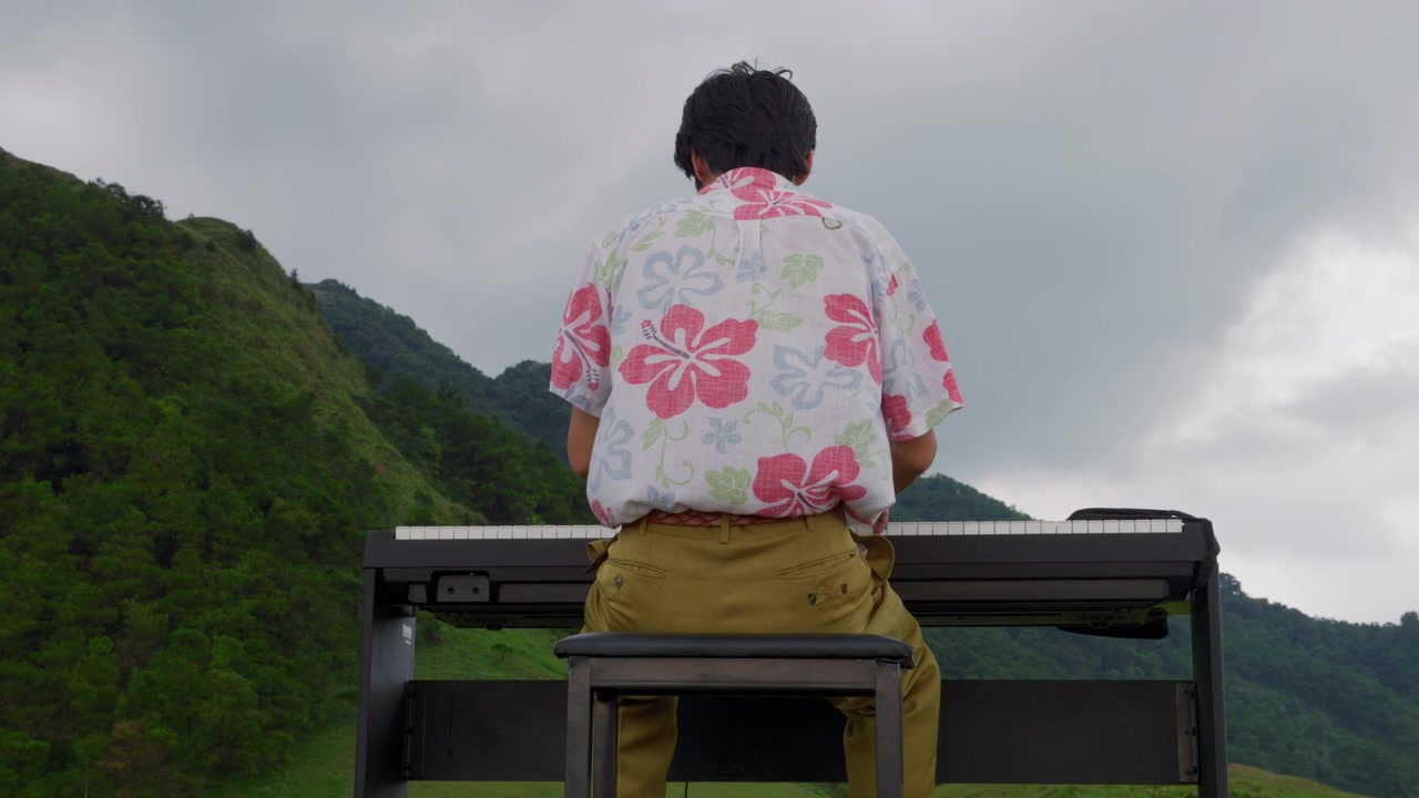 Vintage Asian Male Musician Playing Piano on Mountain Slow Motion Back View