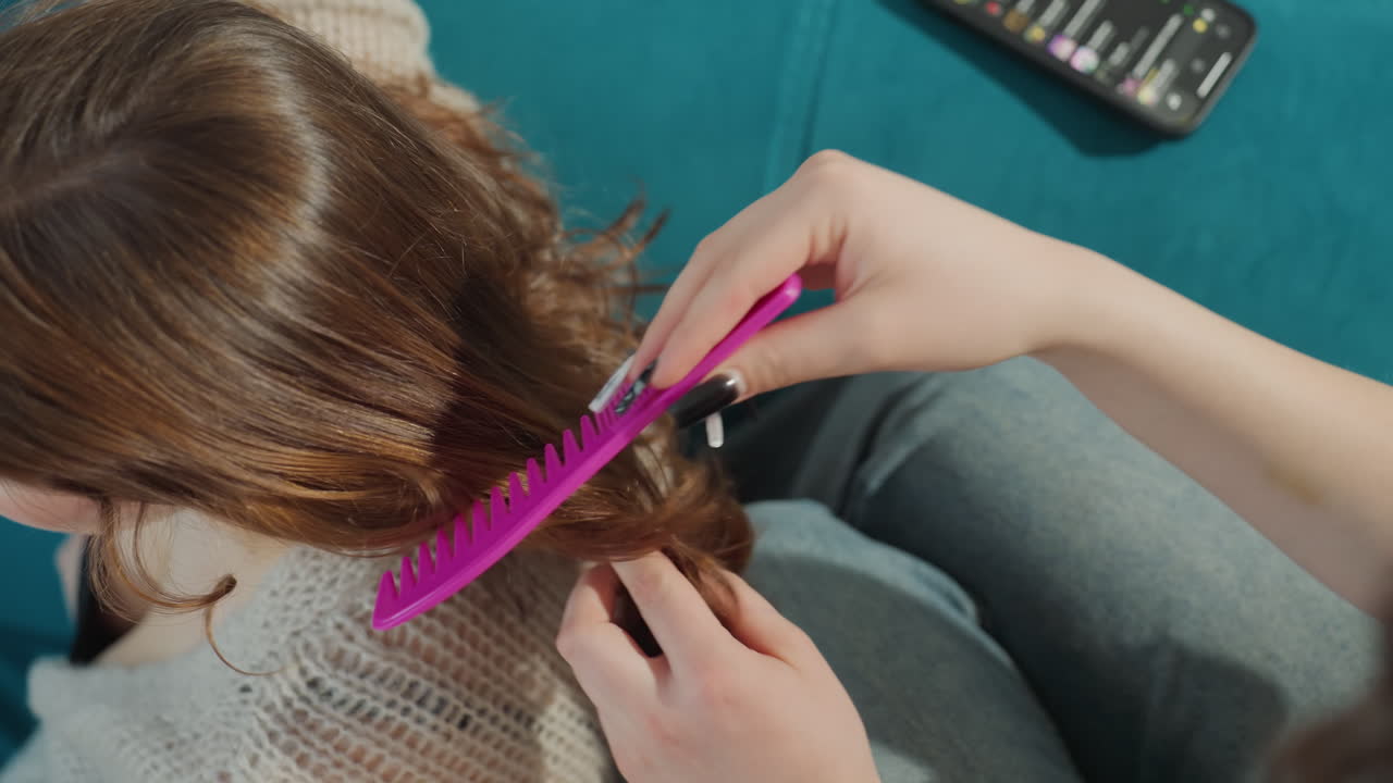 Calm Caretaker Grooming At Home, Nurturing Caregiver Helping Patient Style Hair In Cozy Environment, Gentle Caretaker Organizing Short Hair On Sofa Amid Relaxing Teal Background At Home