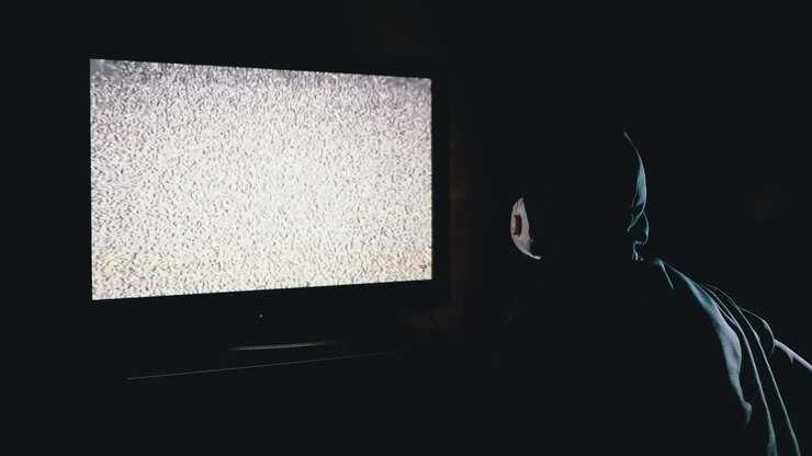 Fake News. Silhouette di uomo con cappuccio e mascherina medica che guarda interferenze TV