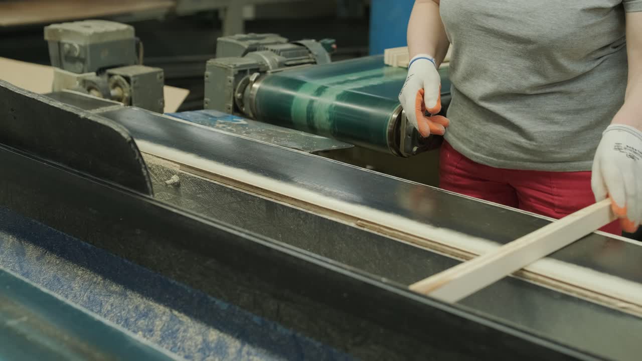 Worker Sorting Wooden Planks on a Conveyor Belt in a Factory