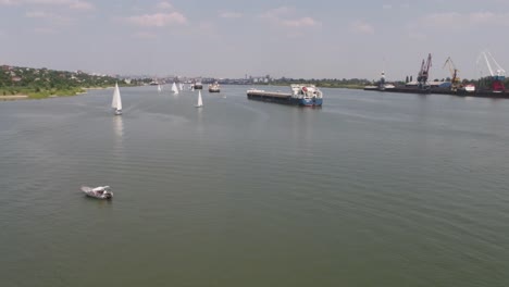 sailboats and cargo ships on a river