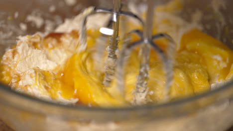 adding egg yokes to the batter then stirring the dough with a hand mixer - close up slow motion
