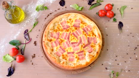 chef in rubber gloves takes bacon pizza on a wooden board from the table.