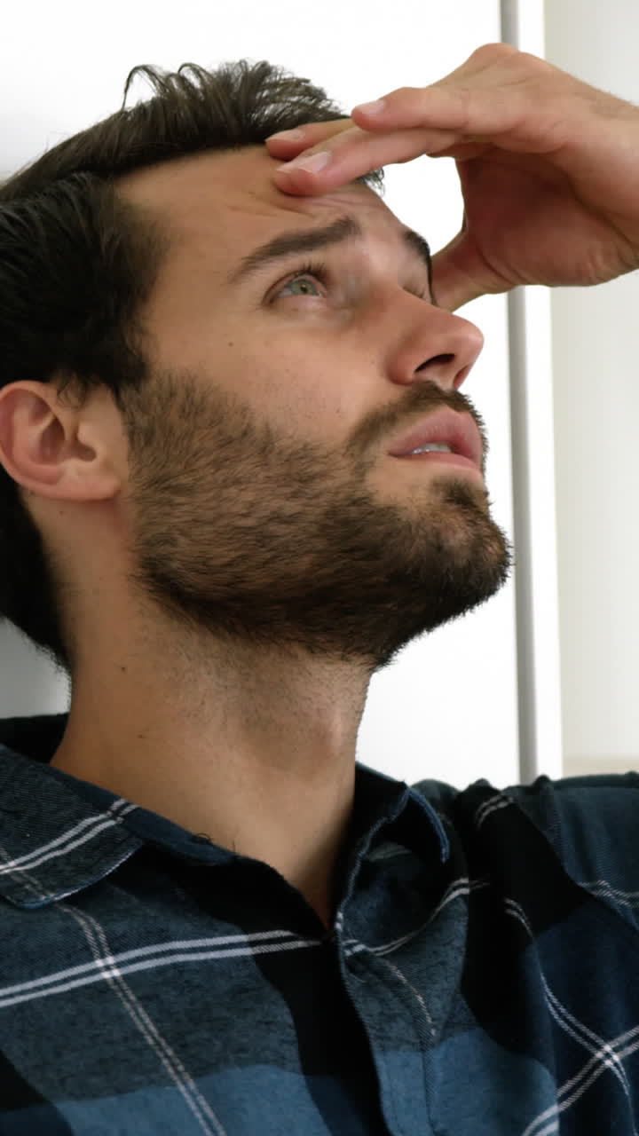 el hombre está de pie contra una pared con una expresión triste en su rostro