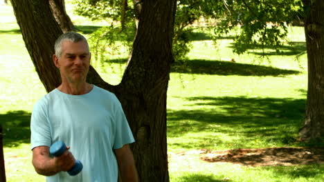 senior man lifting hand weights in the park