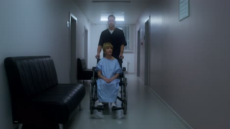 nurse assisting patient in wheelchair in hospital hallway