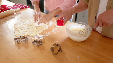 baking christmas cookies, senior asian couple using cutters and mixing batter in kitchen
