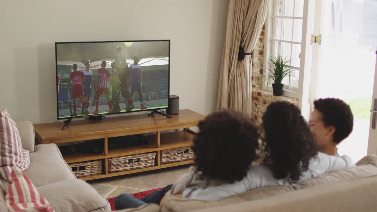 Famiglia felice seduta a casa insieme che guarda una partita di hockey in TV