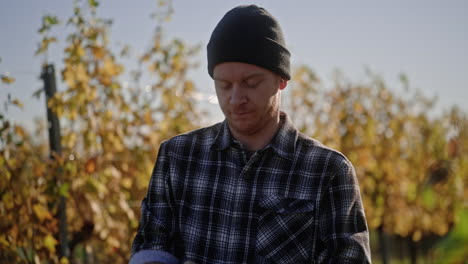 closeup of man in flannel shirt and beanie relaxing on cool autumn day in middle of tree farm