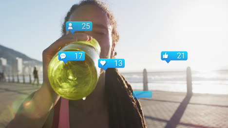 Animation-of-notification-and-number,-biracial-woman-drinking-water-on-promenade-against-sky