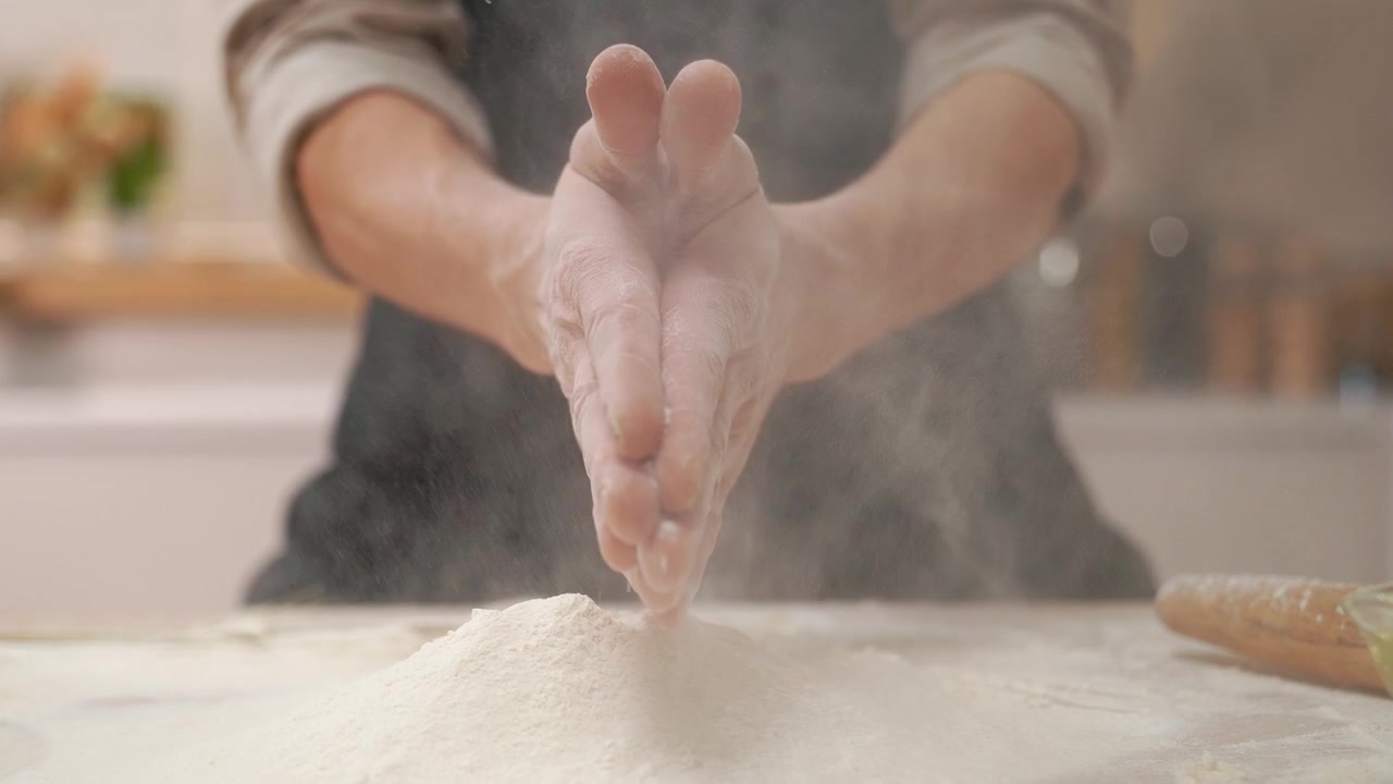 Chef che batte le mani, creando una nuvola di farina