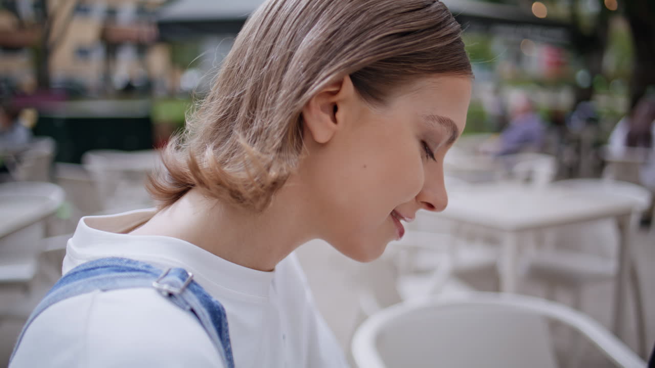 Girl sitting outdoors cafe enjoying carefree summer weekend closeup. Happy woman