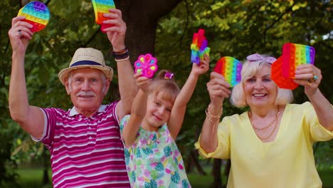 abuela mayor sonriente abuelo con la nieta jugando a apretar juego de juguete anti-estrés