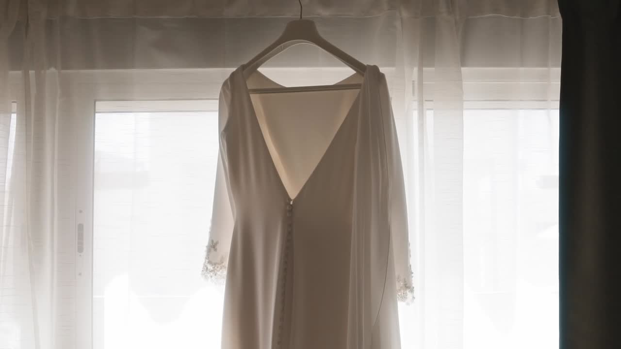 Elegante abito da sposa appeso davanti a una finestra.