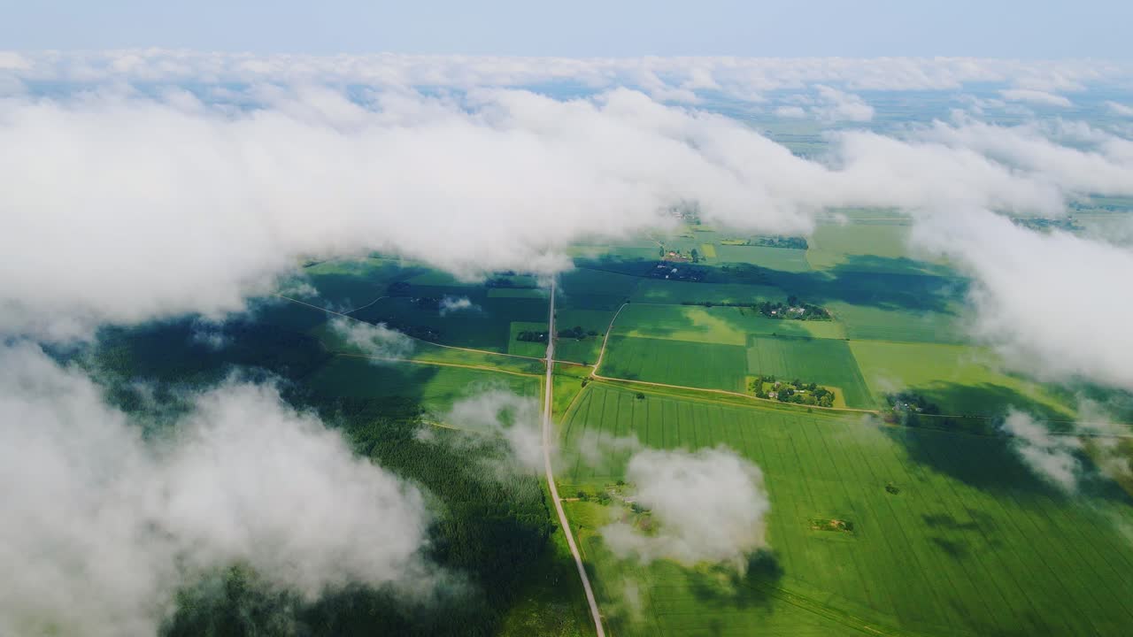 Calm Northern Europe countryside beneath floating white clouds in summer sky