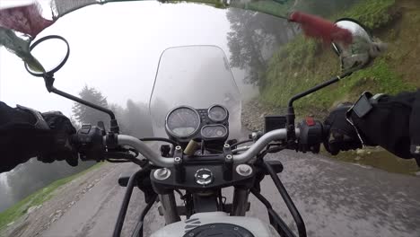 conduciendo una moto a alta velocidad a través de las montañas del himalaya con niebla y pinos