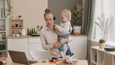 young mother working and holding toddler