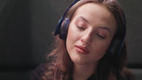 close up of woman with brown hair and long lashes wearing headset, eyes closed, gently nodding head in relaxed rhythm. peaceful moment conveys calmness, focus, and emotional connection to music