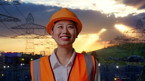 close up of asian female engineer with safety helmet looking around while standing near high voltage tower