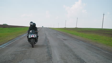 empty road between fields and couple enjoying motoriding