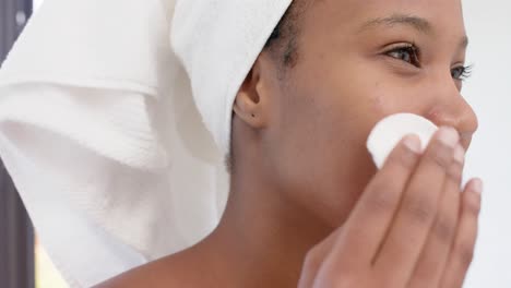 Happy-biracial-woman-with-towel-on-head-washing-her-face,-slow-motion