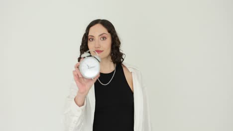 young woman holding an alarm clock on a white background