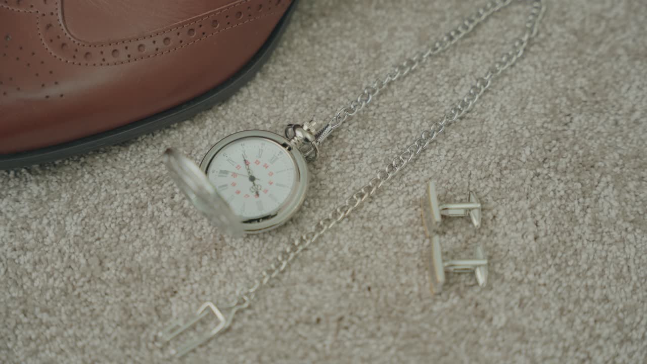 Elegant pocket watch and cufflinks on carpet near brown shoe