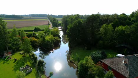 sunlight reflected over stream near rural residential village