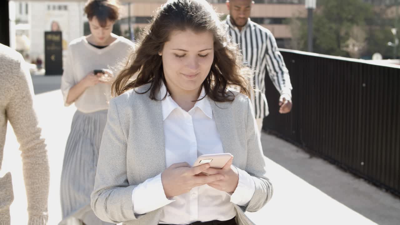 Group of young citizens walking on street with phones