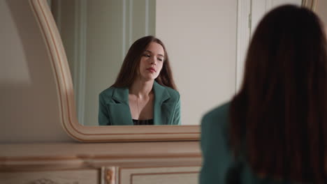 woman in green blazer looking in the mirror