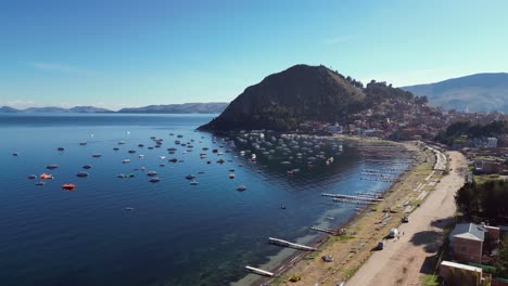 aerial flyover: boats, docks on beach at copacabana on lake titicaca