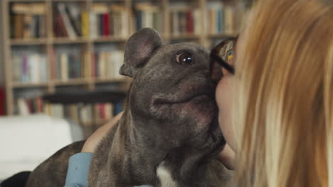 close up view of a red haired woman giving affection and kisses to her bulldog dog