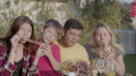 portrait of happy family eating meat at barbecue party