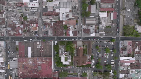 wide top down aerial footage of cars moving down a road in the outskirts of guatemala city, guatemala