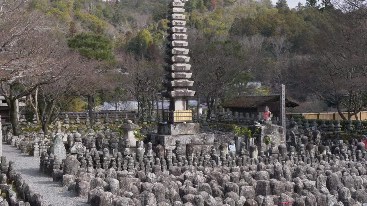 Pemandangan gerak lambat patung-patung batu bersejarah yang berjejer dengan monumen pagoda suci di halaman kuil Adashino Nenbutsuji di Distrik Ukyo Kyoto Jepang, pariwisata dan perjalanan Asia