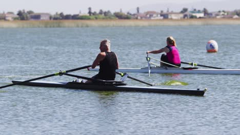 senior caucasian man and woman rowing boat on a river