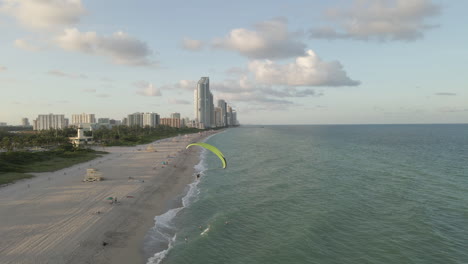 aerial follows acrobatic paramotor flight over haulover beach, miami