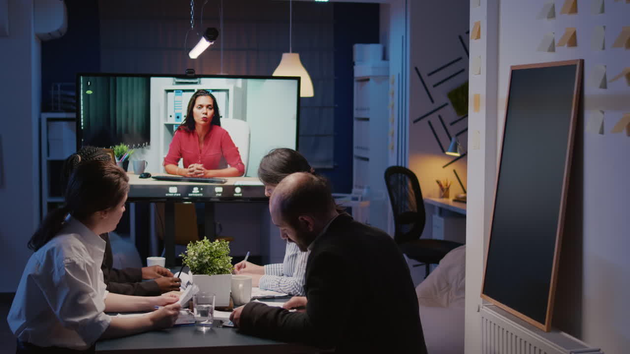 Multi ethnic team overworking in company office room having online videocall conference