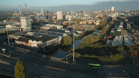 establishing shot of a61 road on outskirts of leeds city centre with green bus and glass bottle factory with chimneys at morning sunrise in west yorkshire uk